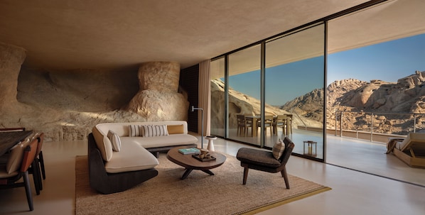 A modern living room with a large window, a sofa, a coffee table, and a chair. - Desert Rock Resort (Umluj)