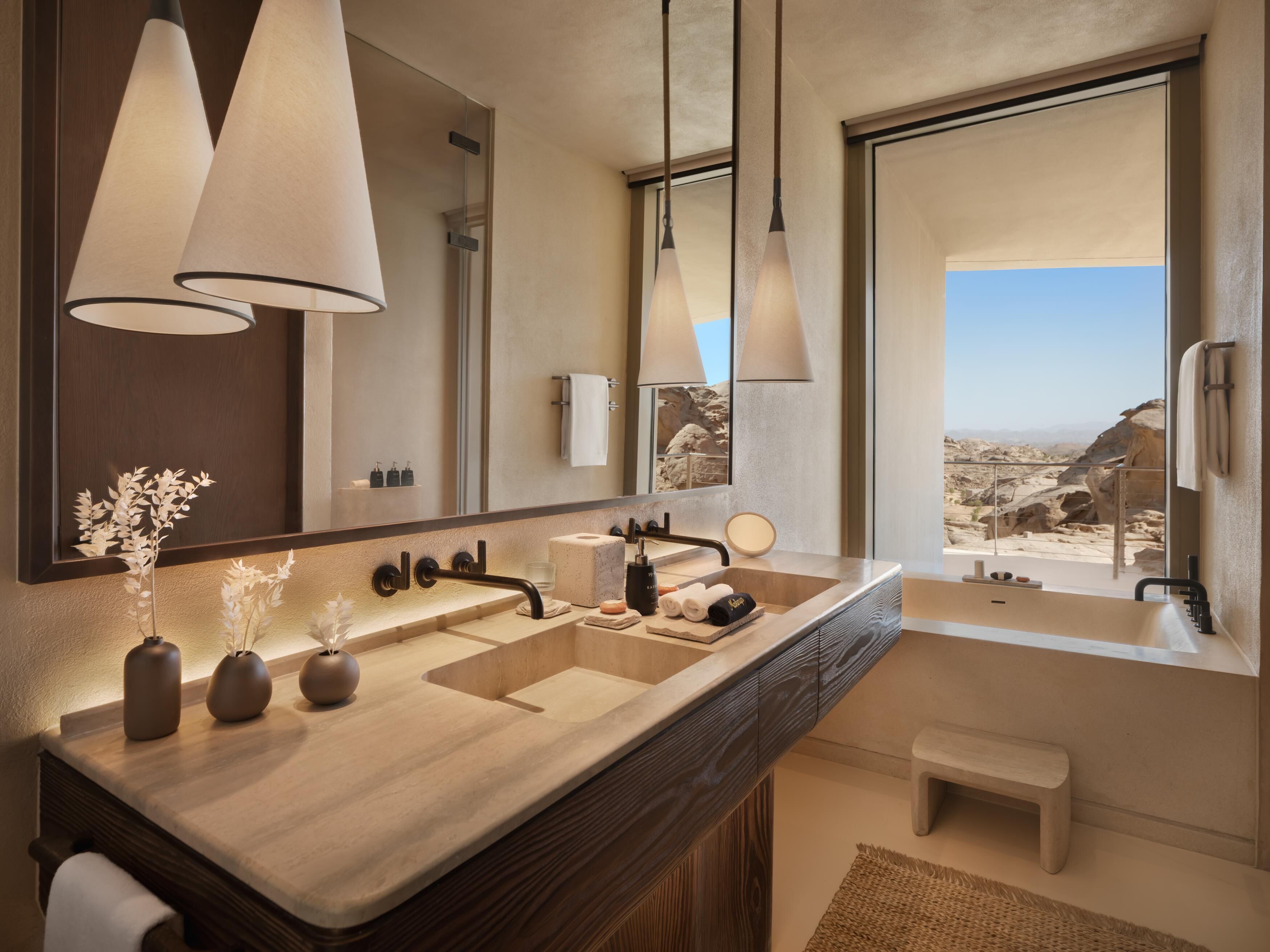 Une salle de bain moderne dotée d’un grand lavabo, de deux miroirs et offrant une vue sur un paysage rocheux.