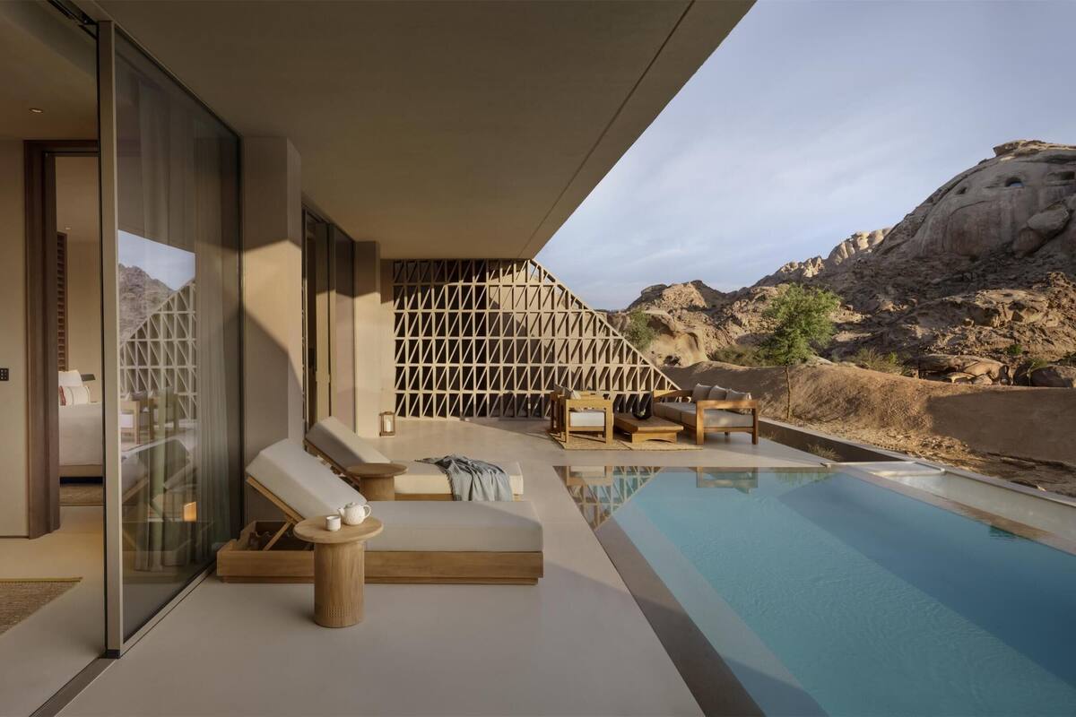 A modern outdoor pool area with lounge chairs and a glass-enclosed room with a bed.