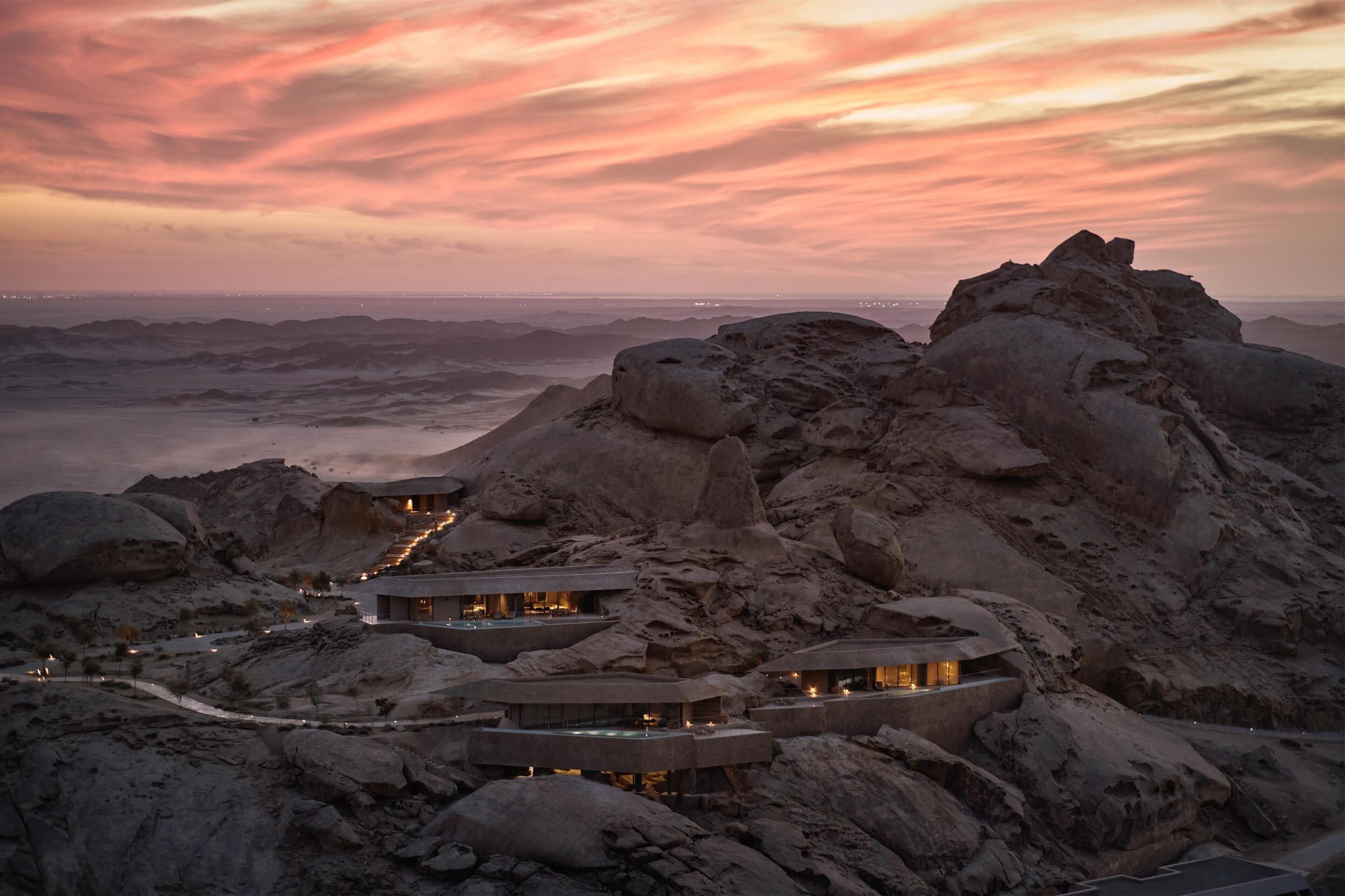 Un complejo turístico en el desierto, con varias construcciones integradas en el terreno rocoso y conectadas por senderos.