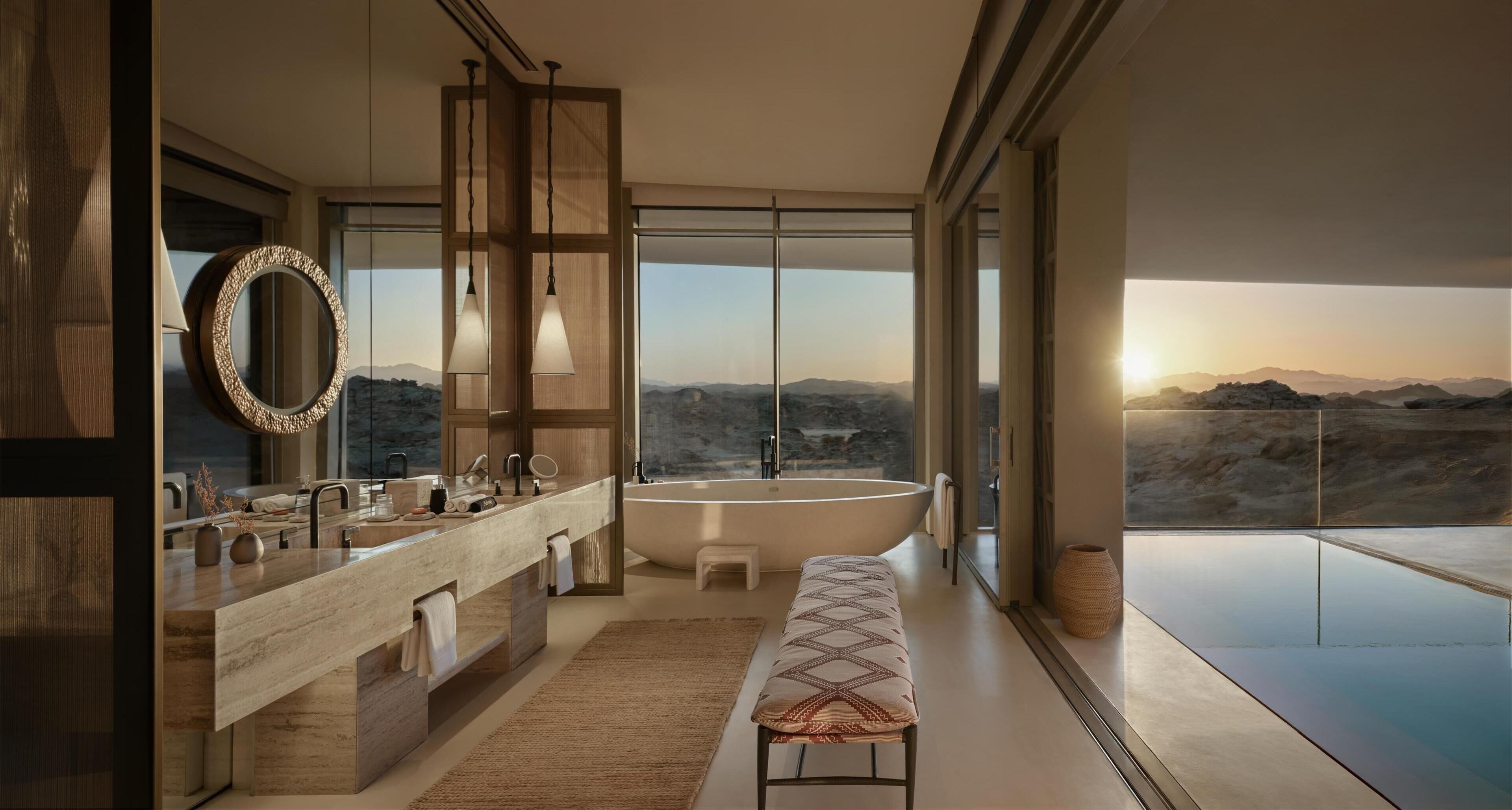 A modern bathroom with a large bathtub, a vanity with a mirror, and a bench.