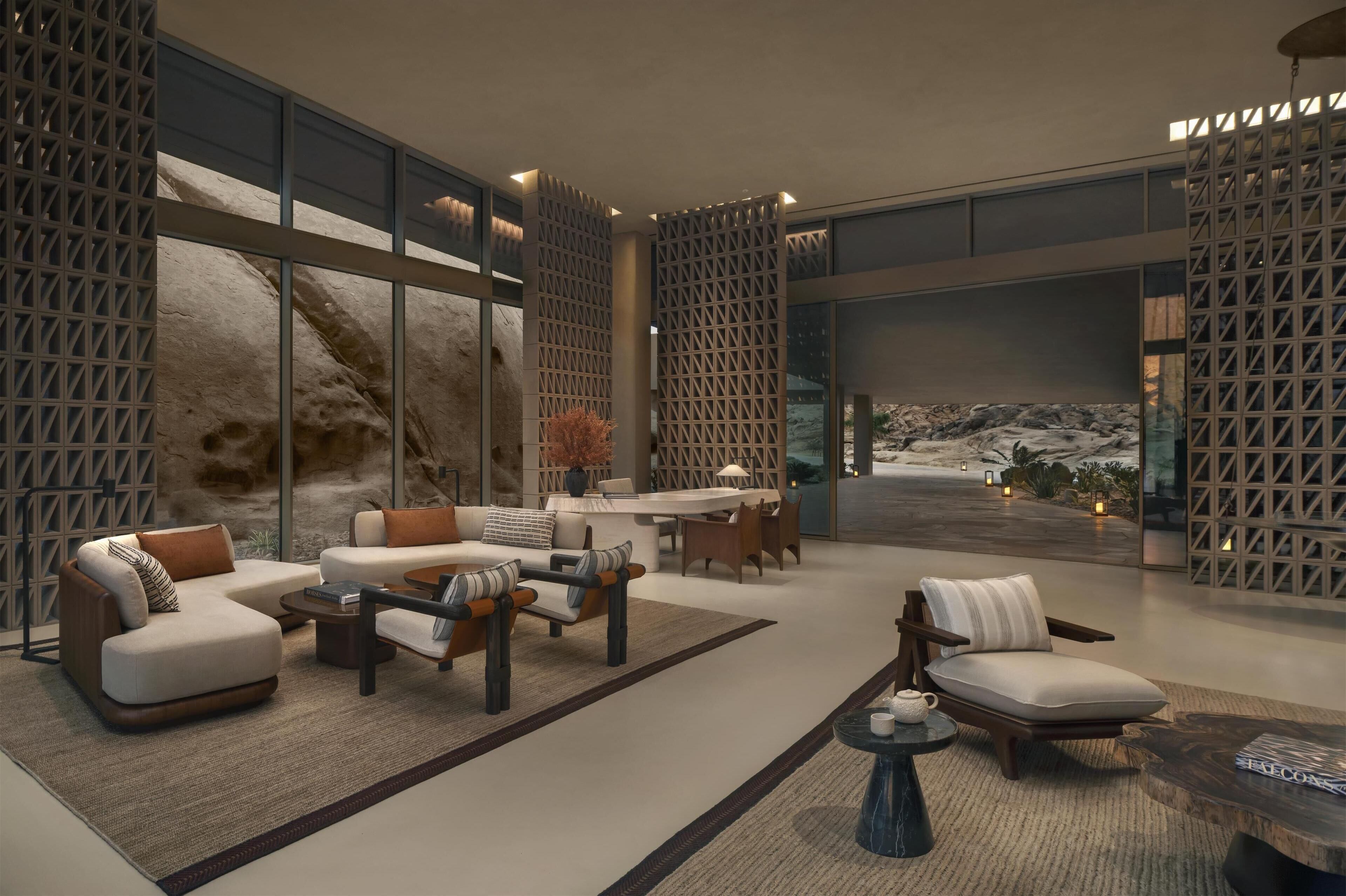 Un vestíbulo amplio con diseño moderno, que cuenta con una generosa zona de estar con sofás y sillones, una mesa de centro y una pequeña mesa con tetera.