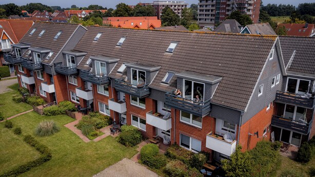 Une rangée d’immeubles d’appartements modernes dotés de balcons, dont certains sont agrémentés de coins salon extérieurs et de verdure.