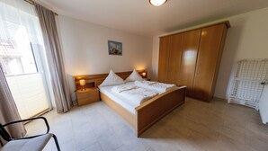 Une chambre à coucher avec un lit en bois, une table de chevet, une chaise, une armoire et un radiateur.
