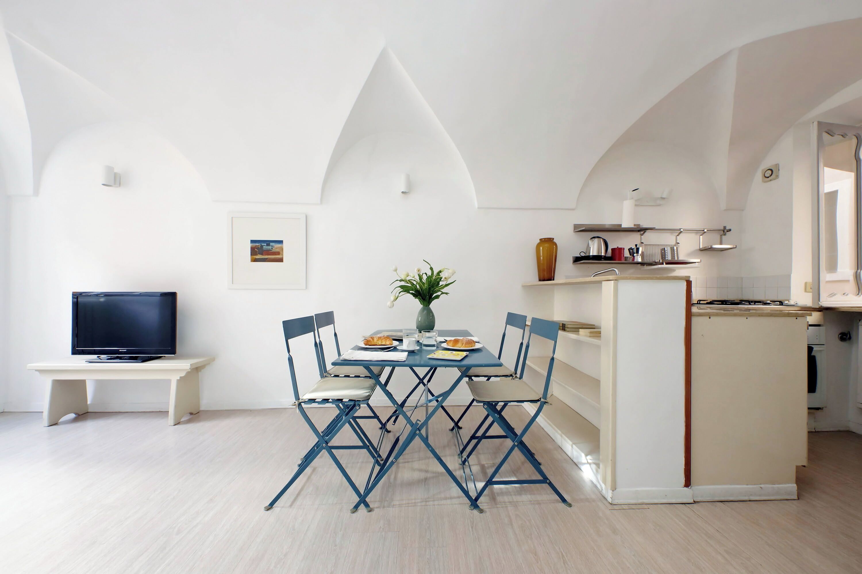 A compact living space with a dining area, kitchenette, and a television on a small table.