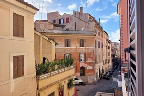A narrow street with buildings on both sides, featuring balconies and a mix of architectural styles. - Cimarra Apartment (Rome)
