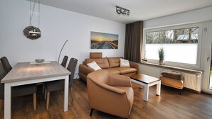 A modern living room with a dining table, sofa, and coffee table. - Fischer's Hus apartment 1<br>Beautiful apartment with terrace and access to the sea time (Büsum)