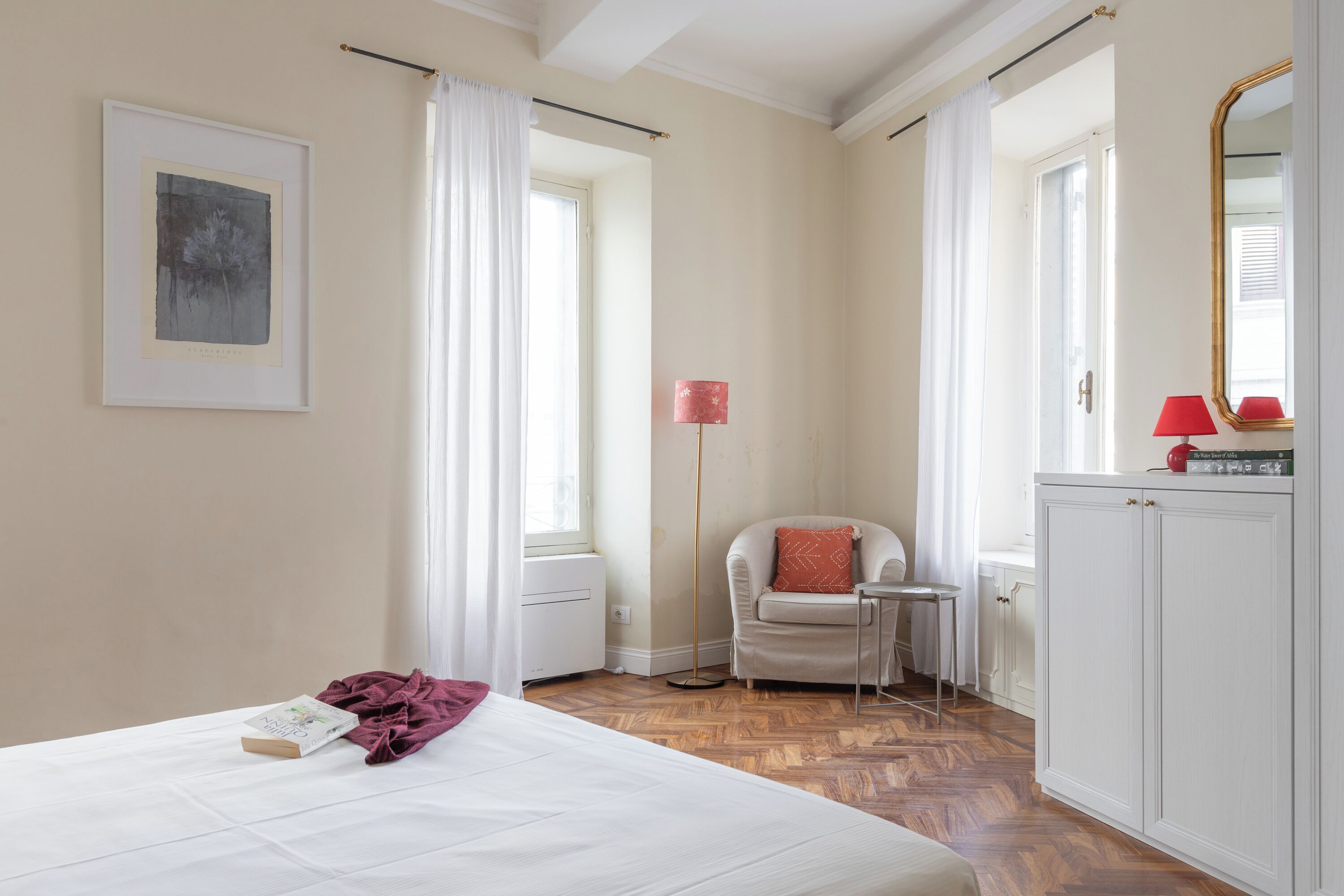 Una camera d'albergo con un letto, una sedia, un tavolino, una lampada da terra e un armadio.