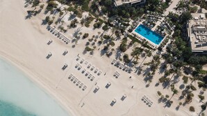 Ein Luftbild eines Strandresorts mit Schwimmbad, Liegestühlen und Palmen.