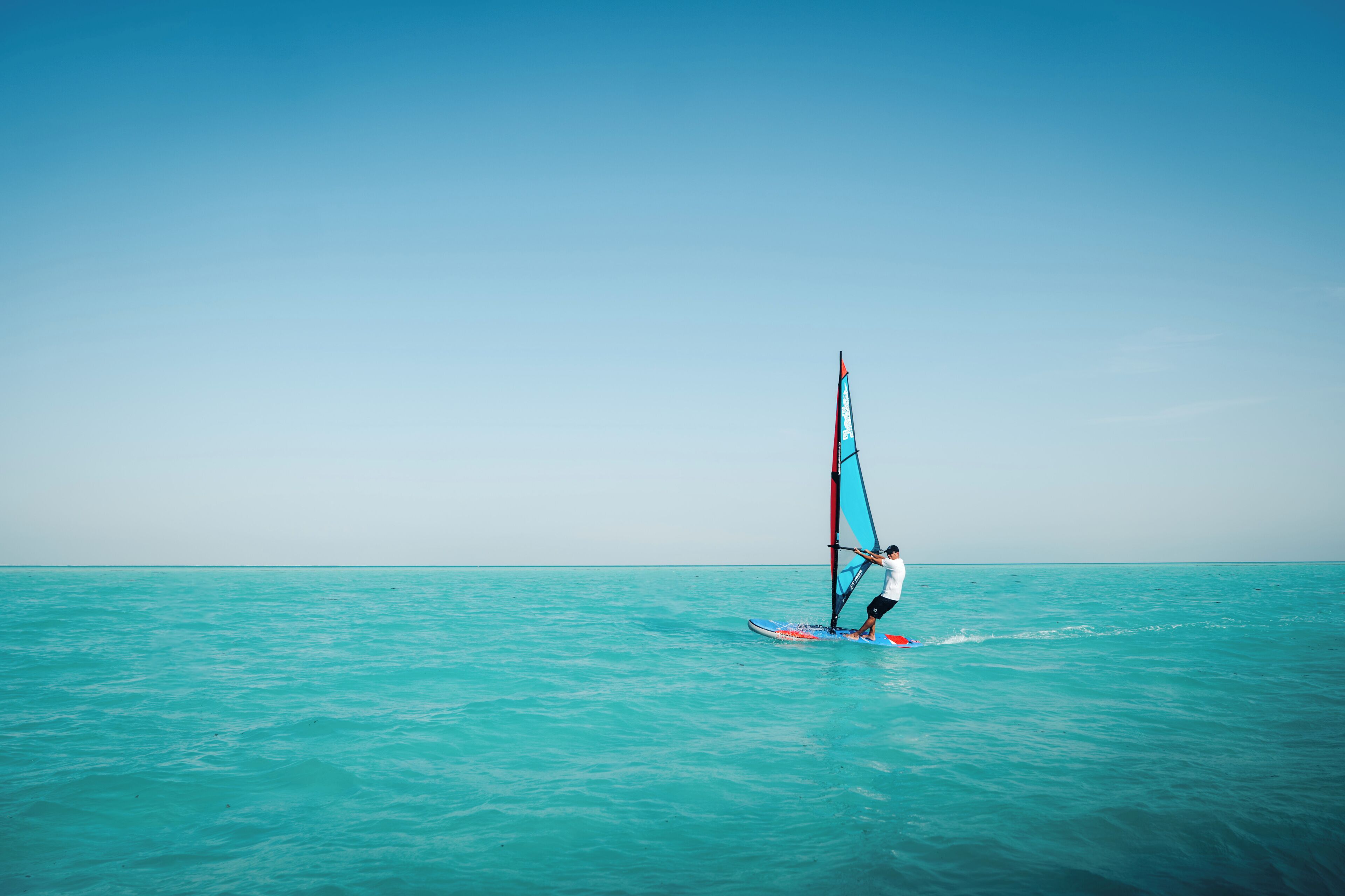 Una persona fent windsurf en un dia clar.