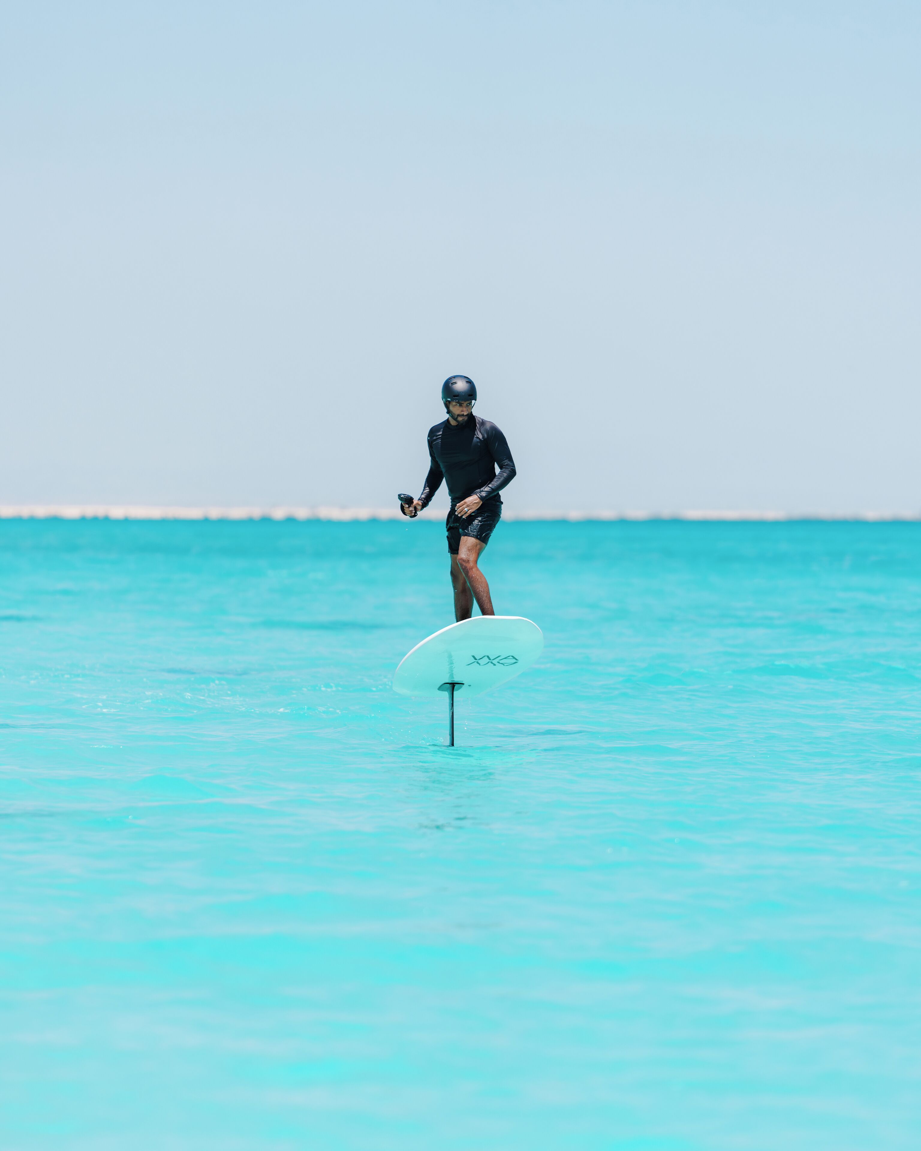 Una persona surfeando en un mar turquesa y transparente.