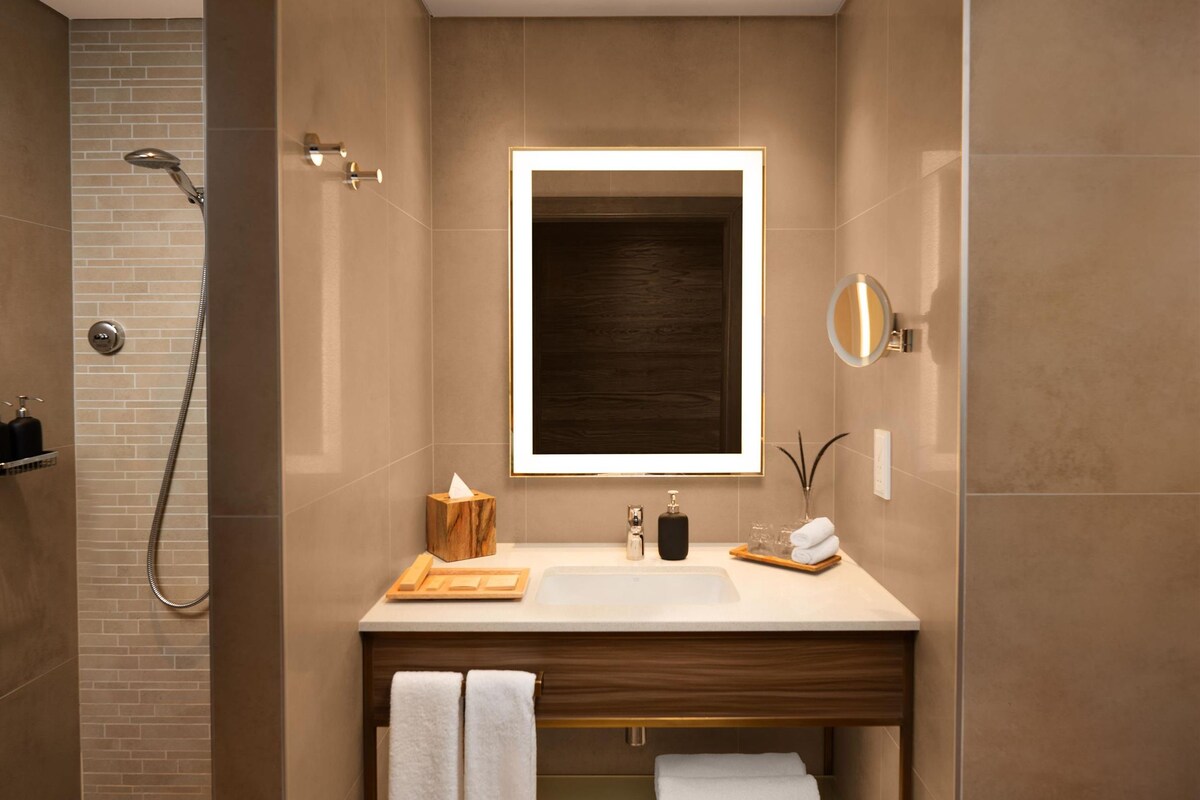 A modern bathroom with a shower, a sink with a mirror, and a towel rack.
