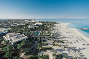 Vista a érea de un resort con playa, piscina y palmeras.