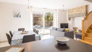 Ein geräumiger Wohnbereich mit Esstisch, Sofa und Fernseher.