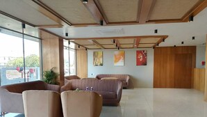 A spacious lobby with modern furniture, large windows, and artwork on the walls. - The Blues Hotel (Sanand)