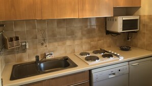A kitchen with wooden cabinets, a stainless steel sink, a Bosch dishwasher, and a white wall-mounted oven. - Ty-Bi - Studio in location vacances in Carnac, Légenèse / Ty-Bihan - UD220 (Carnac)