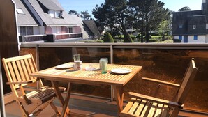 A wooden table and chairs on a balcony with a view of houses and trees. - Ty-Bi - Studio in location vacances in Carnac, Légenèse / Ty-Bihan - UD220 (Carnac)