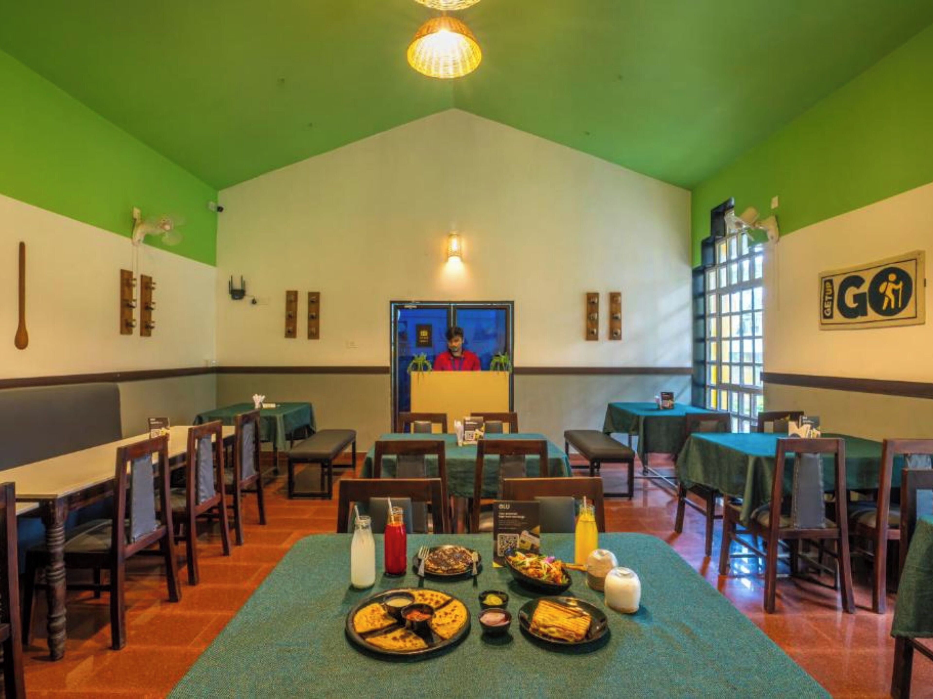 Un restaurant aux couleurs vert et blanc, avec des meubles en bois et une variété de plats disposés sur les tables.