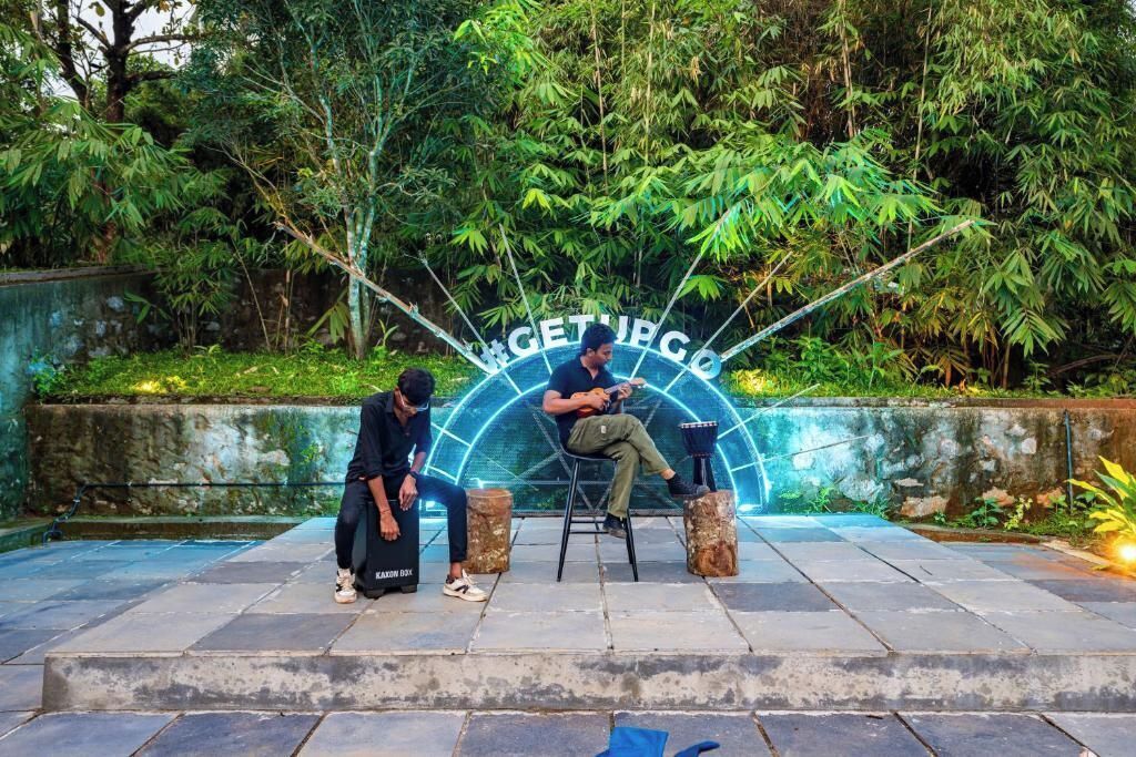 A man sitting on a chair in a garden area with a sign that reads "GET UP GO".