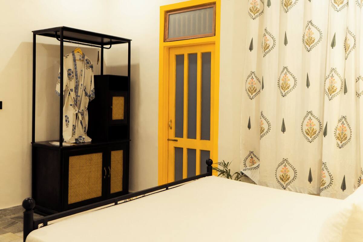 Un dormitorio con cama, ventilador de techo, armario y ventana con cortinas.