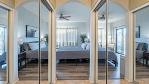 A bedroom with a large bed, a ceiling fan, and a view of the outside through a window. - Luxe Top-Floor Condo|Camelback Views| Heated Pool (Scottsdale)