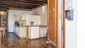 A kitchen with wooden cabinets, a dining table, and a built-in oven. - Giardini 47 - Morada (Cagliari)
