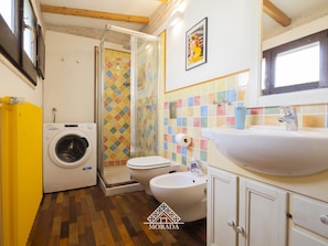 Casa de banho compacta com máquina de lavar, sanita, cabine de duche e lavatório.