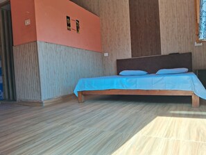 Een slaapkamer met een houten bedframe, een blauw beddegoed en een houten hoofdeinde.