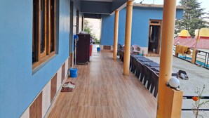 Un couloir doté d’un plancher en bois, de murs bleus et d’un espace abrité avec des chaises et des tables.