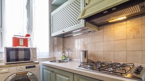 Une cuisine équipée d’un lave-linge, d’un four à micro-ondes, d’une cuisinière à gaz et d’un évier.