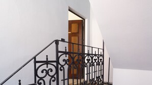 Un escalier orné de rampes en métal noir, menant à une porte en bois.