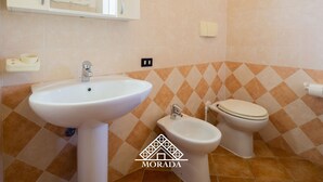 Un baño con lavamanos, bidé, inodoro y espejo.