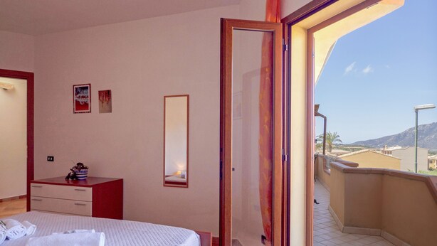 Una habitación de hotel con cama, cómoda, espejo y vistas al exterior.