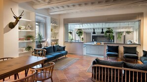 A spacious living area with a dining table, chairs, a sofa, and a kitchen in the background. - Il Casolese Vignamaggio Private Pool  (Greve in Chianti)