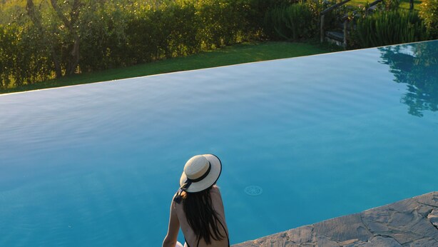 A woman sitting by a pool with a scenic view of hills and trees. - Il Casolese Vignamaggio Private Pool  (Greve in Chianti)