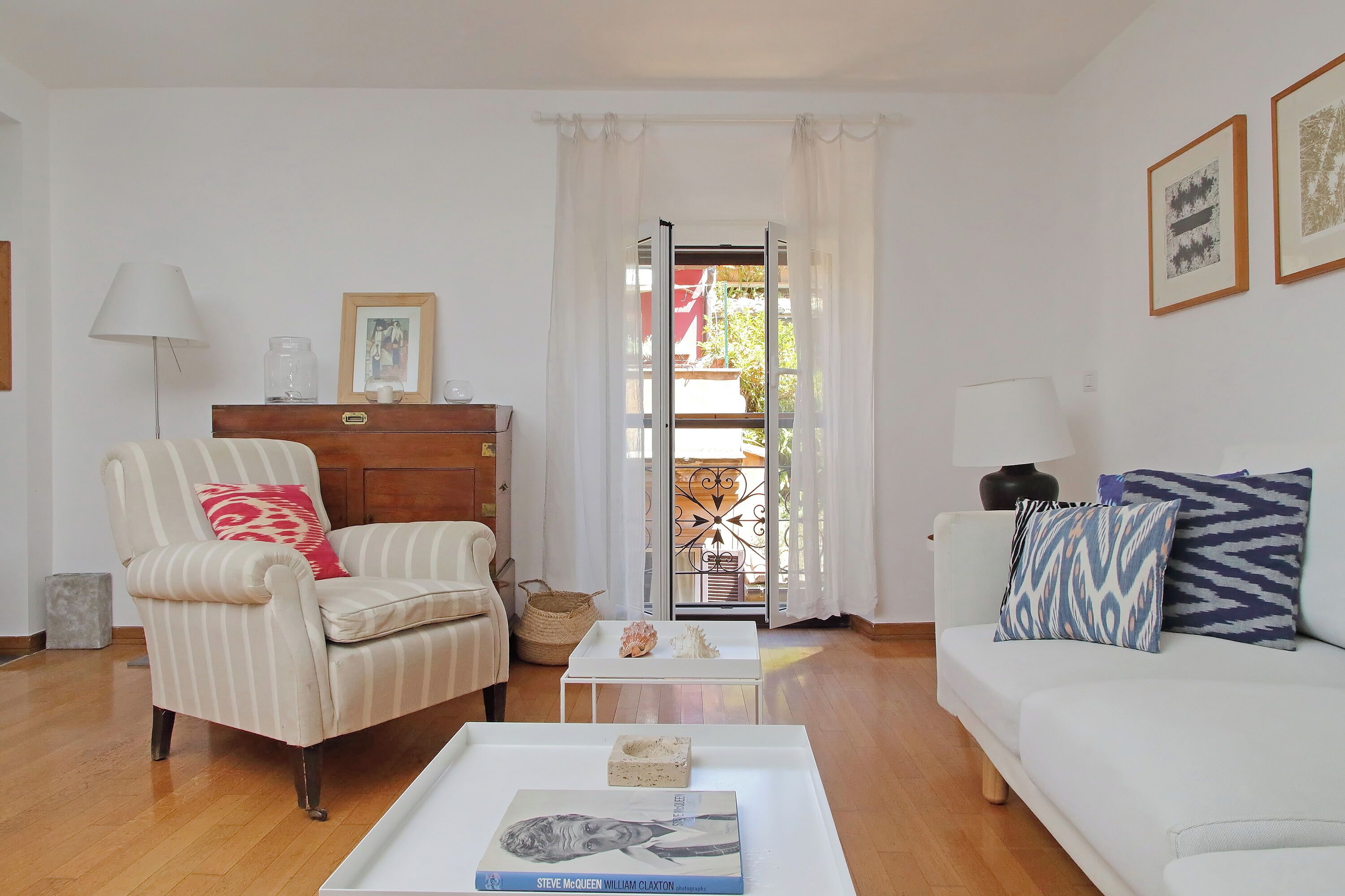 Un salon comprenant un canapé, un fauteuil, une table basse et une vue sur l’extérieur, visible à travers une porte vitrée.