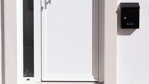 Une porte blanche avec une poignée, un panneau de verre et une boîte aux lettres portant le numéro 11, fixée au mur.