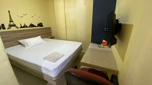 Een hotelkamer met een bed, een bureau, een stoel, een televisie en een muur met een stadsgezicht sticker.