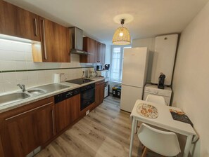 A modern kitchen with wooden cabinets, a dishwasher, a stove, and a refrigerator. - Over time (Morlaix)