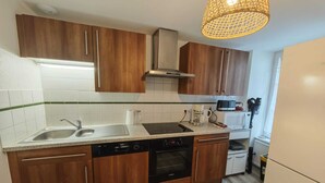 Una cocina moderna con armarios de madera, un lavamanos de acero inoxidable, un lavavajillas Bosch, un microondas y una tetera.