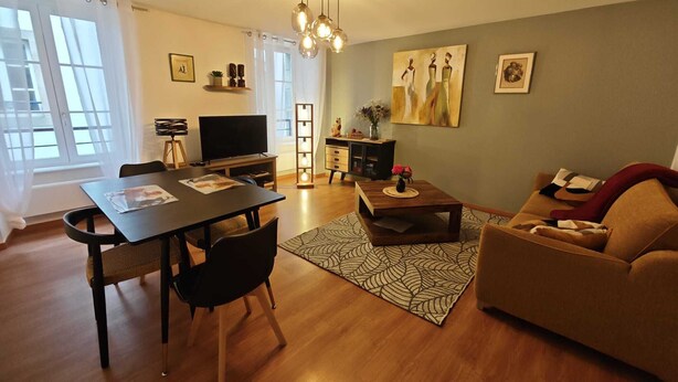 Una sala de estar moderna con comedor, un sofá, un televisor y obras de arte en las paredes.