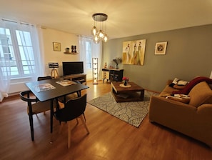 Una sala de estar moderna con comedor, un sofá, un televisor y obras de arte en las paredes.