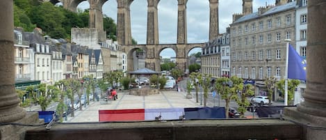 A view of a historic stone bridge with multiple arches, surrounded by buildings and a flag.