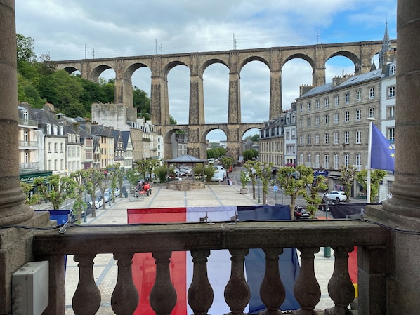 Vista de un puente de piedra histórico con varios arcos, rodeado de edificios y una bandera.