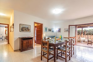 A dining area with a wooden table and chairs, a cabinet, and framed pictures on the wall. - Scacciapensieri (Olbia)