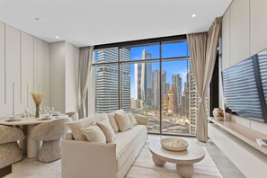 A modern living room with a large window, a sofa, a dining table, and a TV.