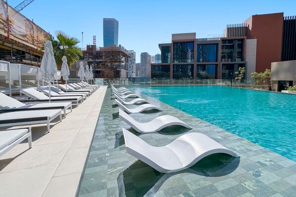 A modern pool area with lounge chairs and a clear view of the city skyline.