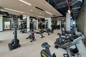 A spacious gym with various exercise equipment, including treadmills, stationary bikes, and weight machines.