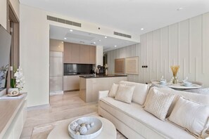 A modern living room with a sofa, a coffee table, and a dining area with a table and chairs.