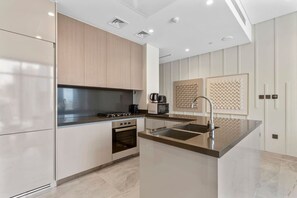 Een moderne keuken met een centraal eiland, roestvrijstalen apparatuur en een minimalistisch ontwerp.